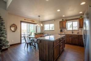 A spacious kitchen with wooden cabinets, a central island, and a dining area with chairs.