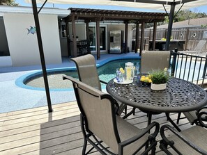 Ett område vid poolen med en pergola, utomhusmöbler och en pool.