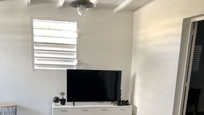Una sala de estar moderna con un televisor de pantalla plana, una mesa de centro de vidrio y un sofá.