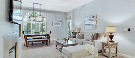 A spacious living room with a ceiling fan, a dining area with a bench and table, and a cozy seating area with a couch and side tables.