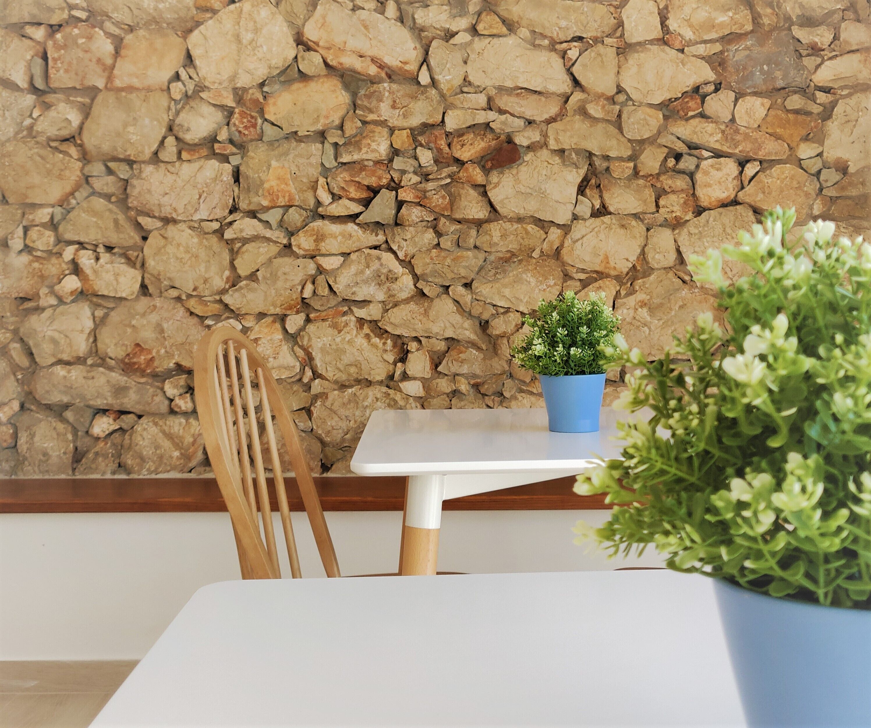 Een tafel met een potplant, een stoel en een stenen muur op de achtergrond.