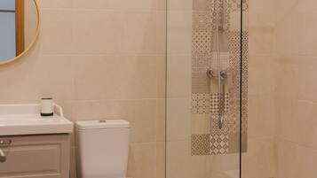 A modern bathroom with a toilet, bidet, and glass-enclosed shower.