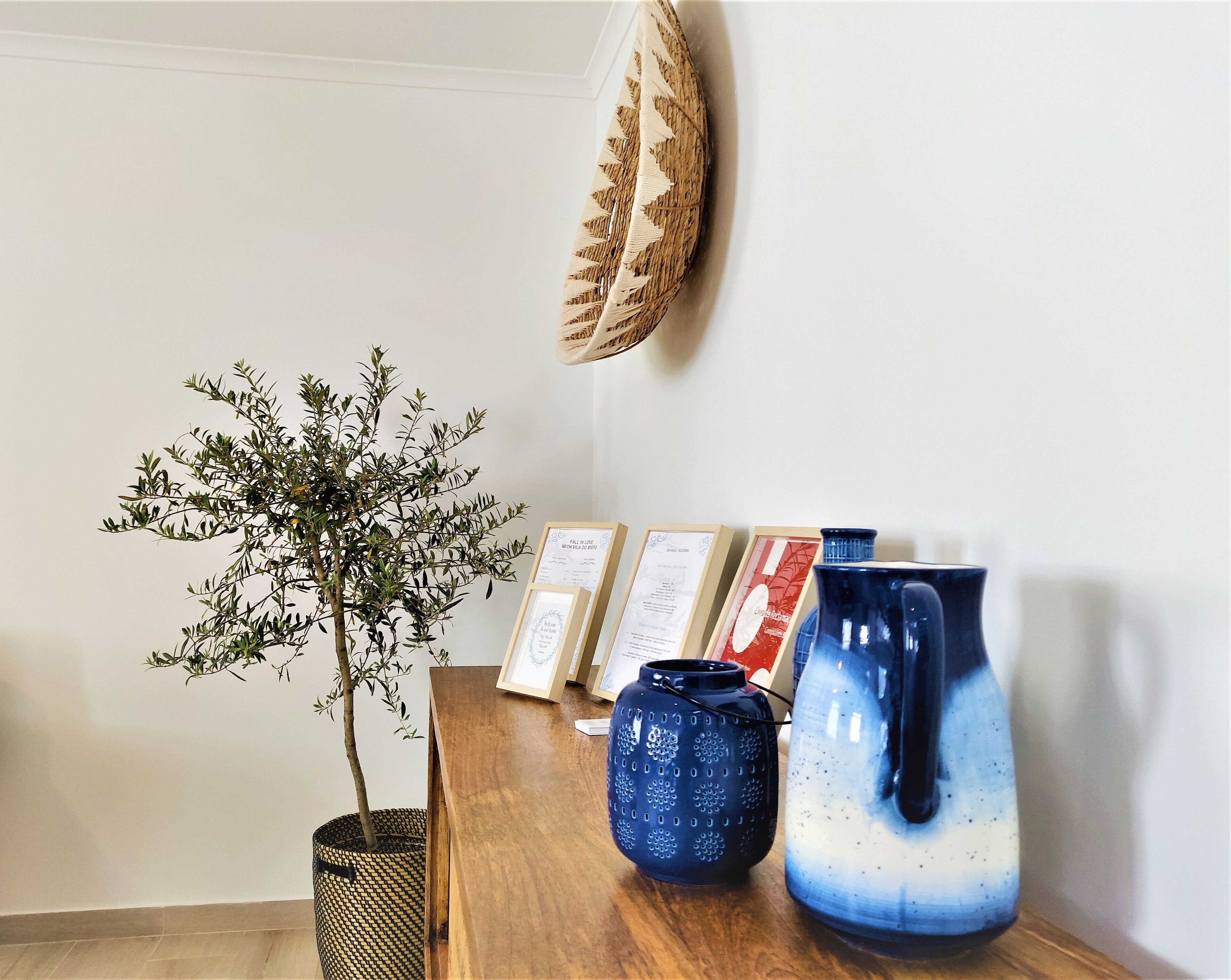 A wooden table with a potted plant, framed certificates, and two ceramic vases.