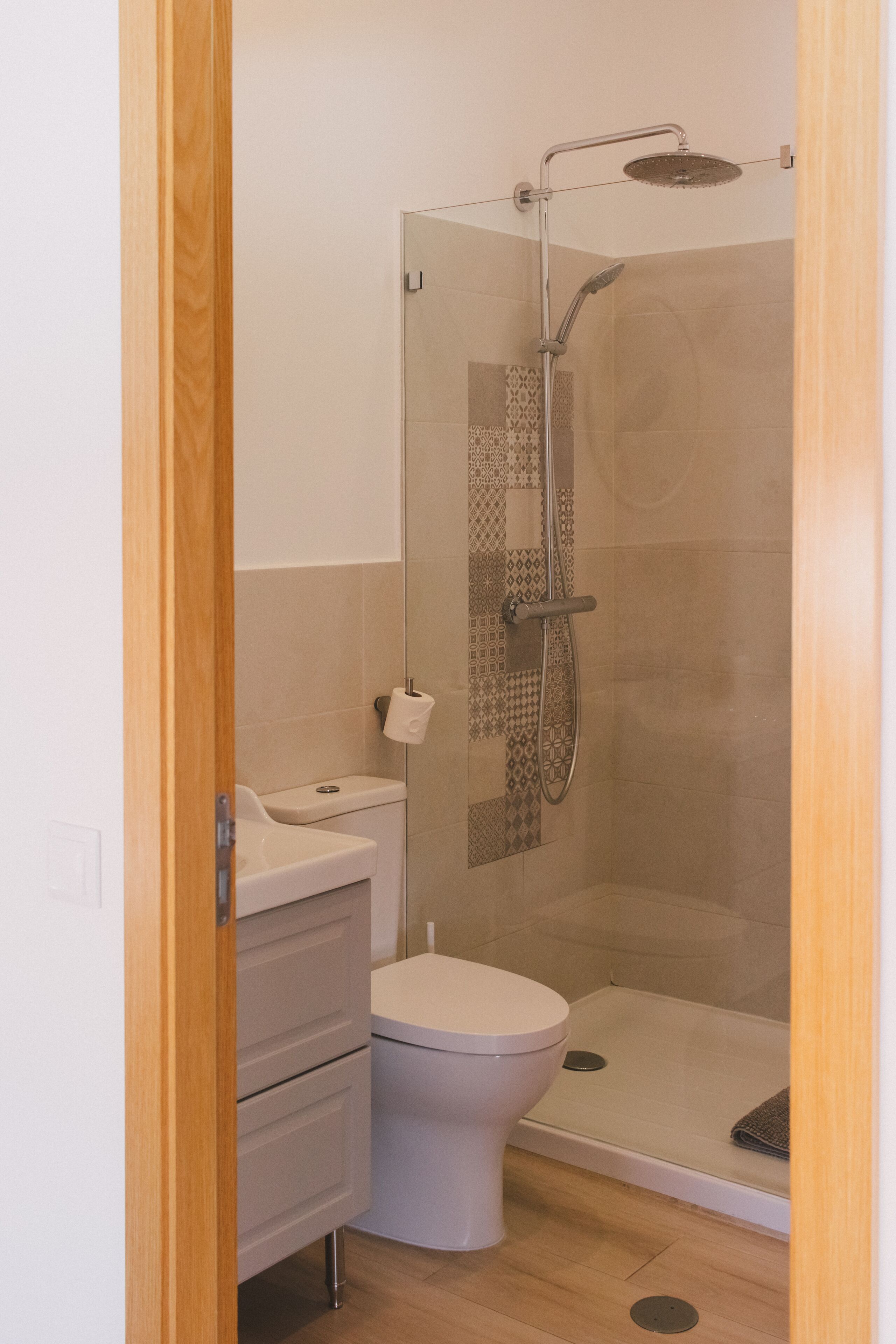 Une salle de bain moderne avec une douche à parois de verre, des toilettes blanches et un meuble-lavabo en bois.