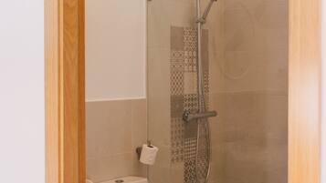 Une salle de bain moderne avec une douche à parois de verre, des toilettes blanches et un meuble-lavabo en bois.