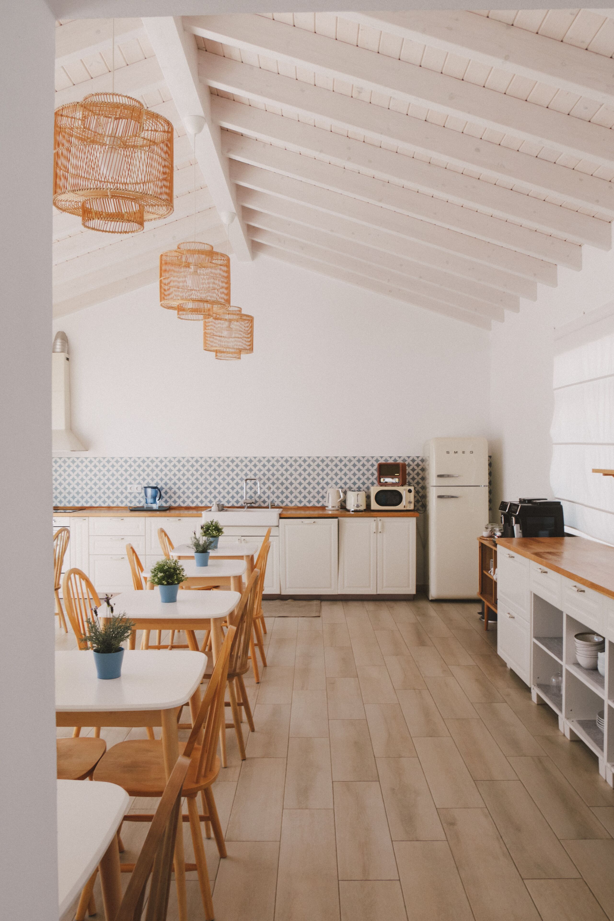 A modern kitchen with white cabinetry, wooden flooring, and a herringbone ceiling.