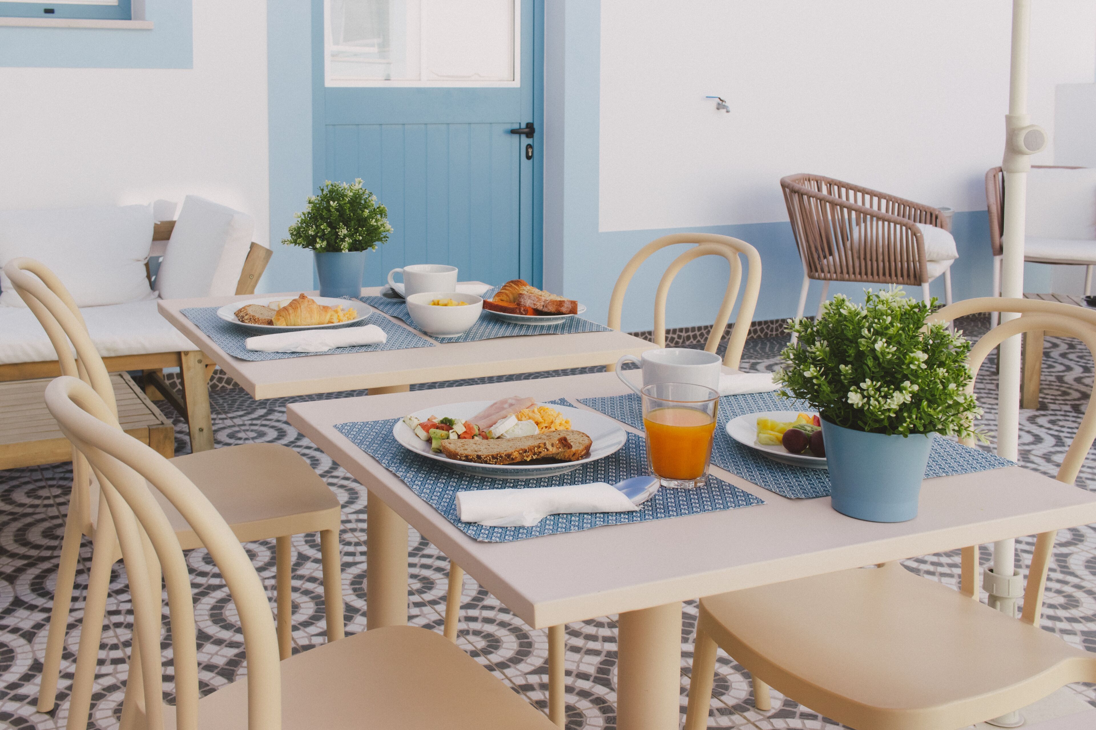 Ein Essbereich mit einem Tisch, der für das Frühstück gedeckt ist, darunter Croissants, Obst und ein Glas Orangensaft.
