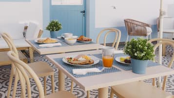 Un coin repas avec une table mise pour le petit-déjeuner, comprenant des croissants, des fruits et un verre de jus d’orange.