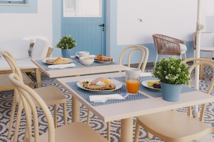 Ein Essbereich mit einem Tisch, der für das Frühstück gedeckt ist, darunter Croissants, Obst und ein Glas Orangensaft.