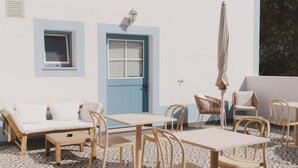 A room with a blue door, a window, a sofa, and several chairs.
