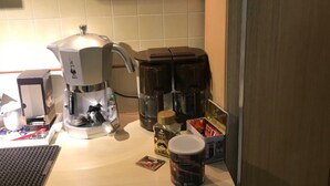 Keittiössä on kahvinkeitin, vedenkeitin ja espressokone. Lisäksi siellä on useita kahvikuppeja ja purkki sokeria.