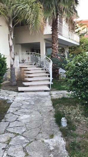 A stone staircase leading to a building with a white railing, surrounded by greenery and a palm tree. - Villa Susanna (Brindisi)