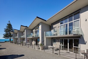 Un hotel moderno con varios balcones, amplias ventanas y vistas al mar.