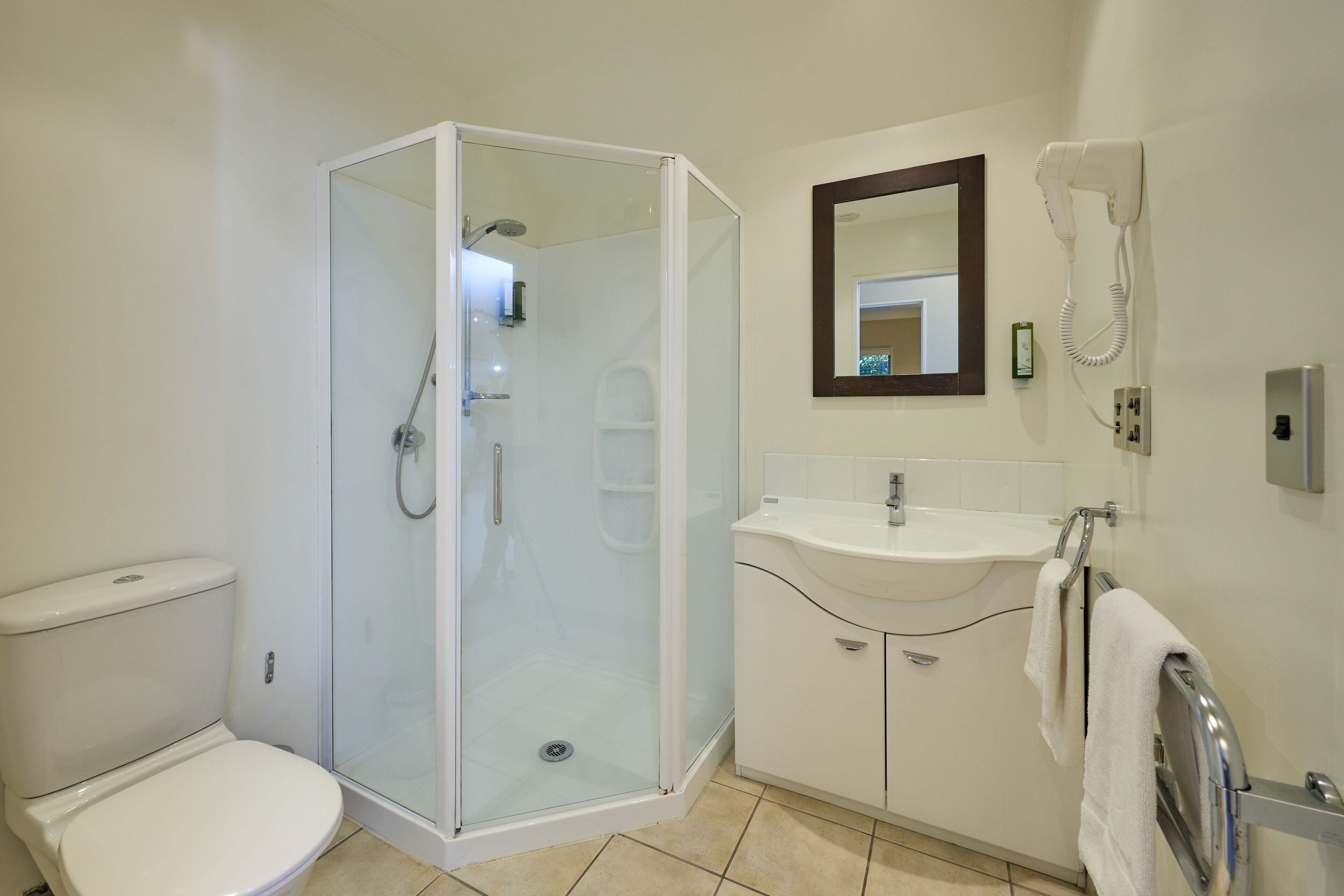 A modern bathroom with a glass-enclosed shower, a white sink, and a toilet.