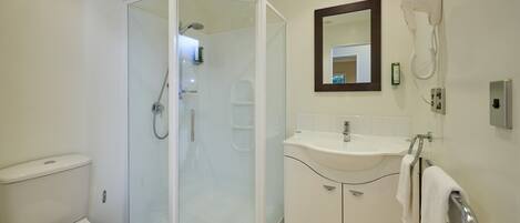 A modern bathroom with a glass-enclosed shower, a white sink, and a toilet.