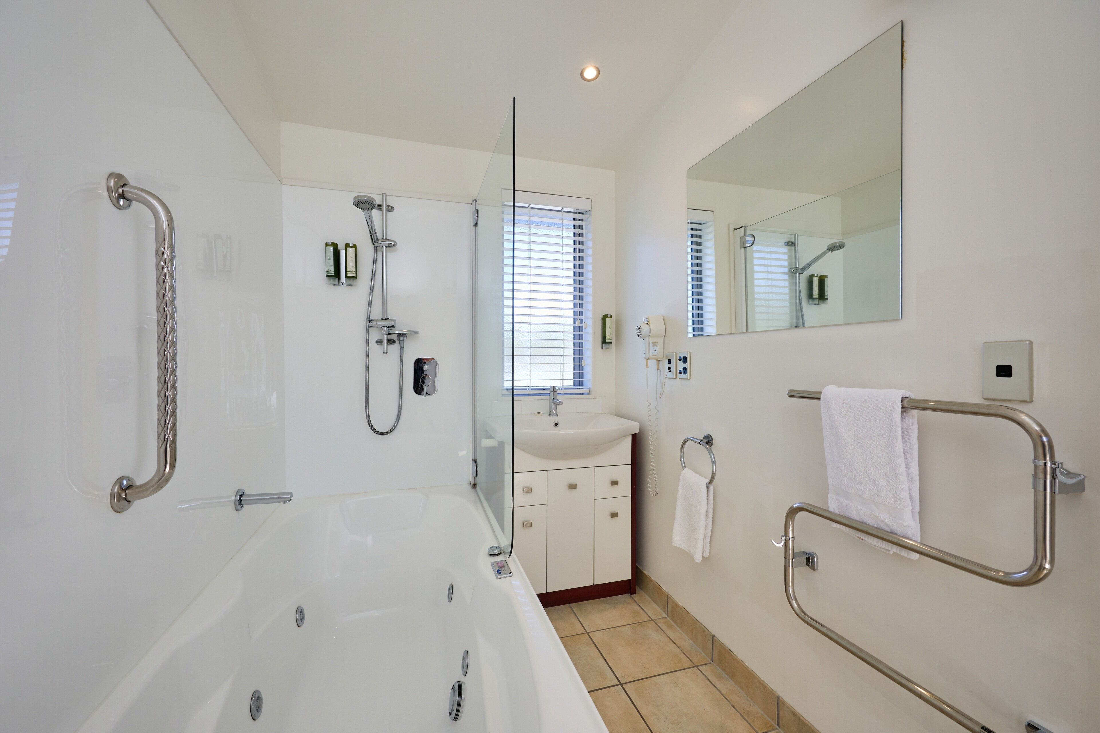 Une salle de bain moderne dotée d’une grande baignoire, d’une douche à parois de verre, d’un lavabo et d’un miroir.