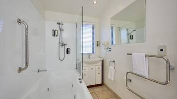 Une salle de bain moderne dotée d’une grande baignoire, d’une douche à parois de verre, d’un lavabo et d’un miroir.