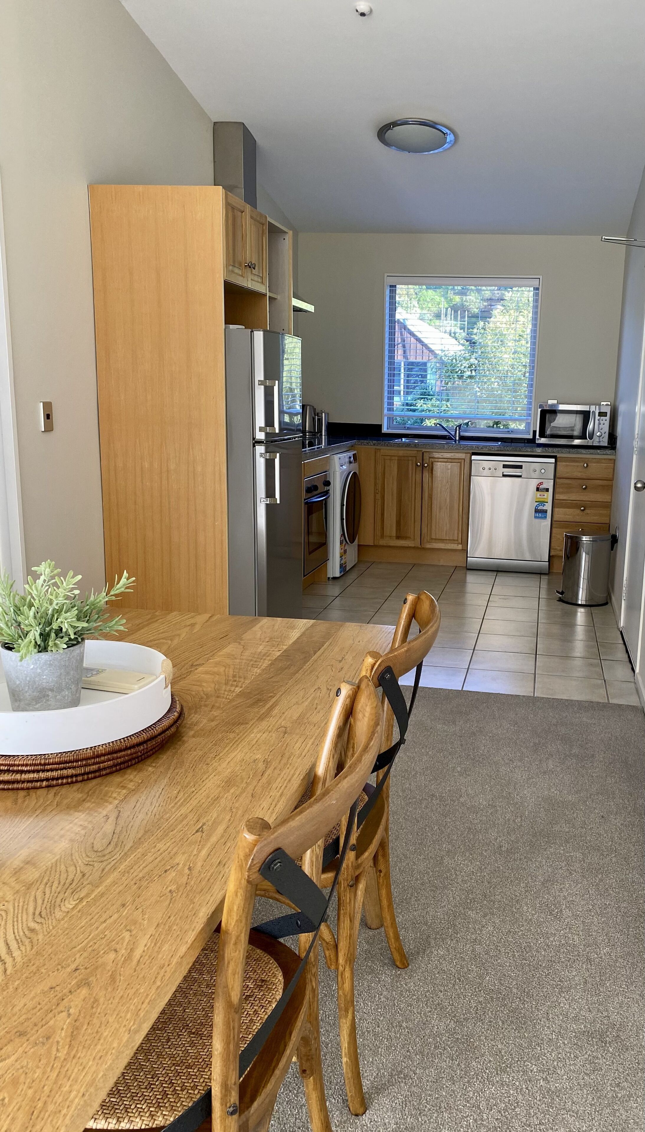 A modern kitchen with wooden cabinets, stainless steel appliances, and a dining area with a wooden table and chairs.