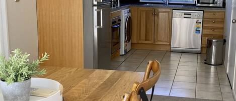 A modern kitchen with wooden cabinets, stainless steel appliances, and a dining area with a wooden table and chairs.
