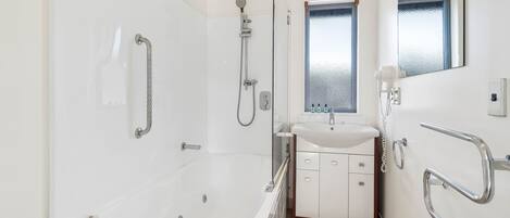 A modern bathroom with a walk-in shower, a bathtub, a sink, and a mirror.