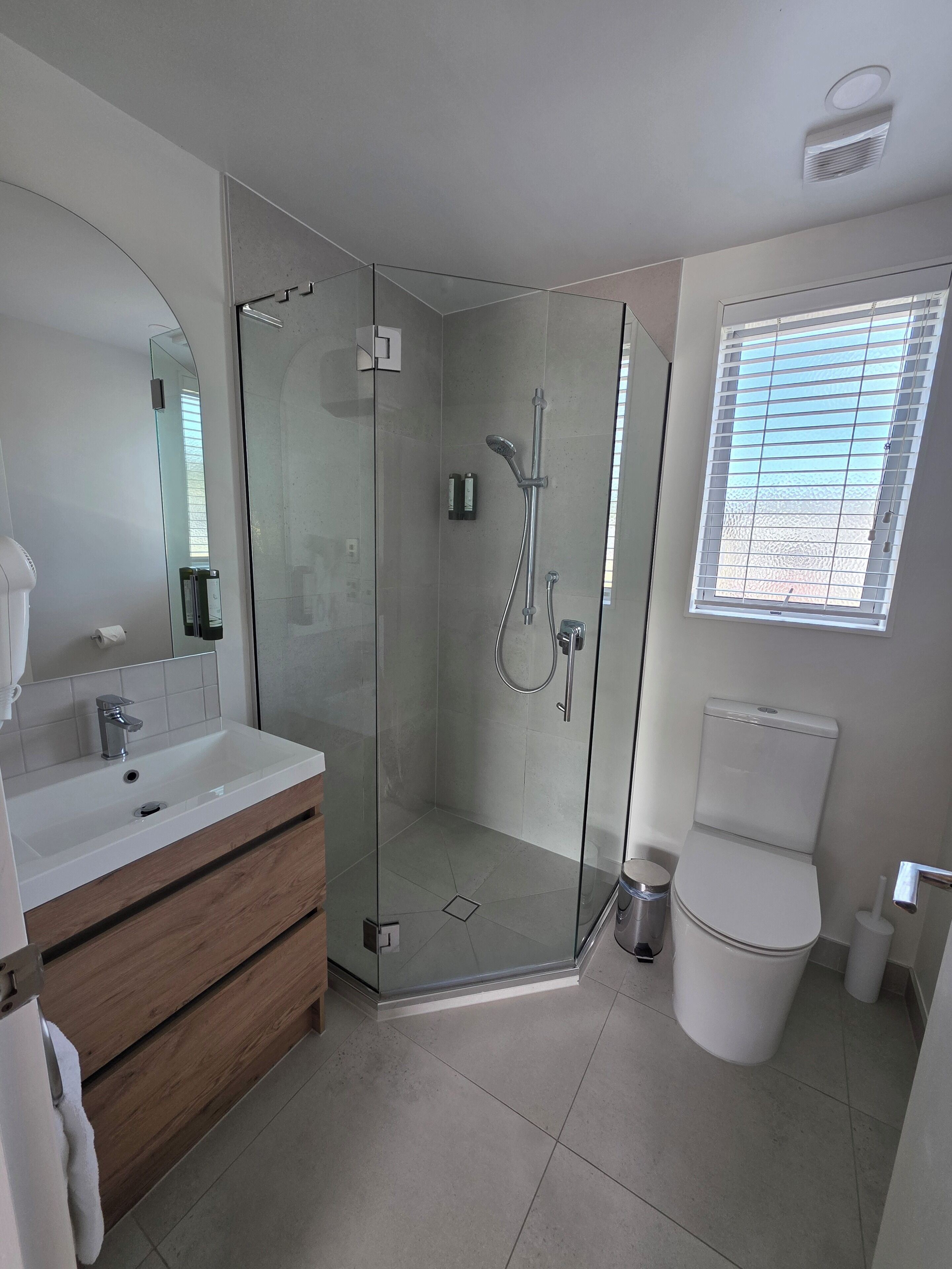 A modern bathroom with a glass-enclosed shower, a white sink, and a toilet.