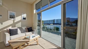 A modern living room with a sofa, a coffee table, and a large sliding glass door leading to a balcony.