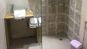 A bathroom with a glass partition, a shower, a mirror, and a tiled backsplash. - Chez Daniel mbene (Mbour)