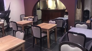 A restaurant with wooden tables and chairs, a bar area, and a decorative chandelier. - Chez Daniel mbene (Mbour)