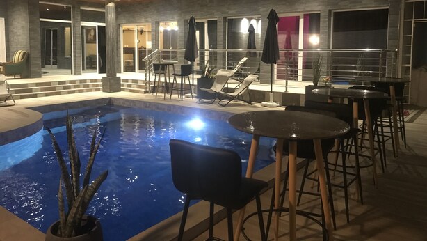 A modern outdoor pool area with lounge chairs and a bar. - Chez Daniel mbene (Mbour)