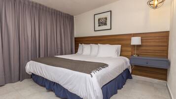 A neatly made bed with a wooden headboard, a bedside table with a lamp, and a framed picture on the wall.