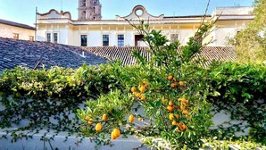 Un edificio con tejado de tejas y una torre de campanas al fondo.