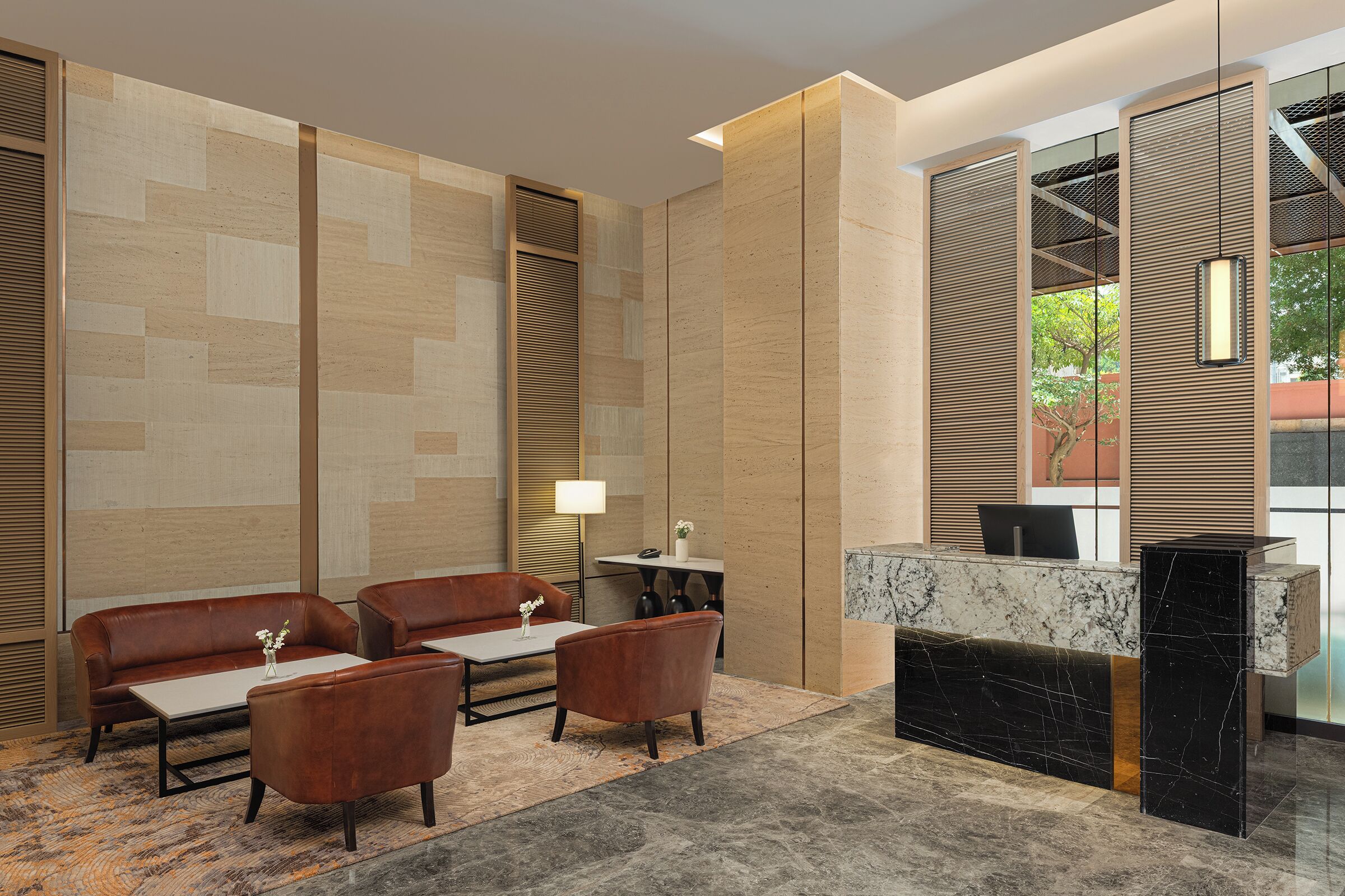 A modern lobby with a reception desk, leather sofas, and a patterned carpet.