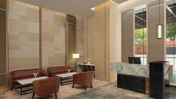 A modern lobby with a reception desk, leather sofas, and a patterned carpet.