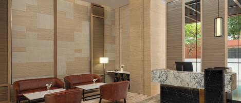 A modern lobby with a reception desk, leather sofas, and a patterned carpet.