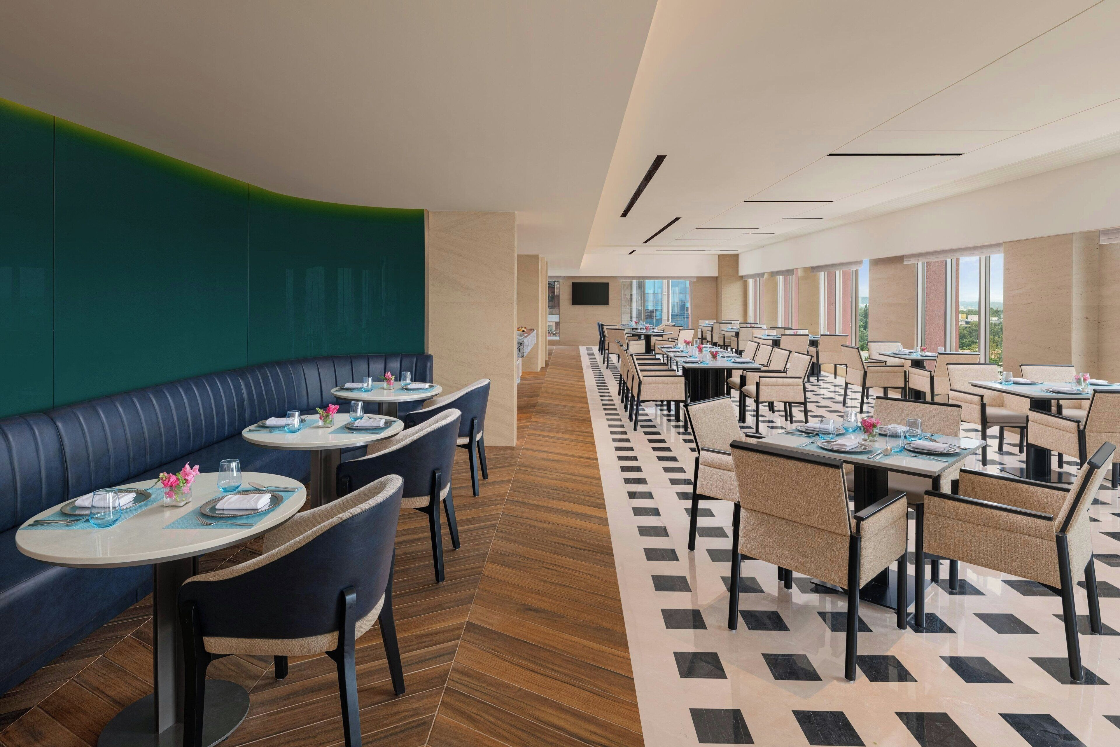 En moderne restaurant med både båse og borde, et mønstret gulv og store vinduer med udsigt.