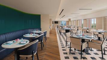 En moderne restaurant med både båse og borde, et mønstret gulv og store vinduer med udsigt.