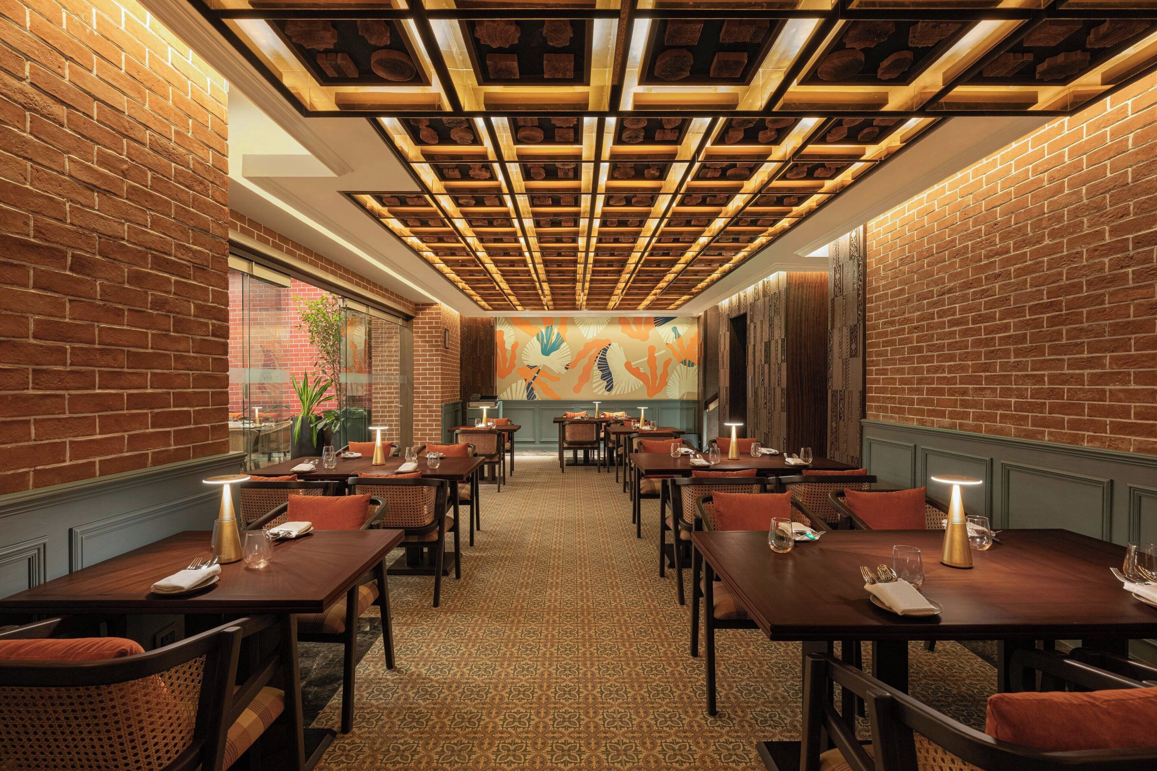 A restaurant with brick walls, wooden ceiling, and tables set for dining.
