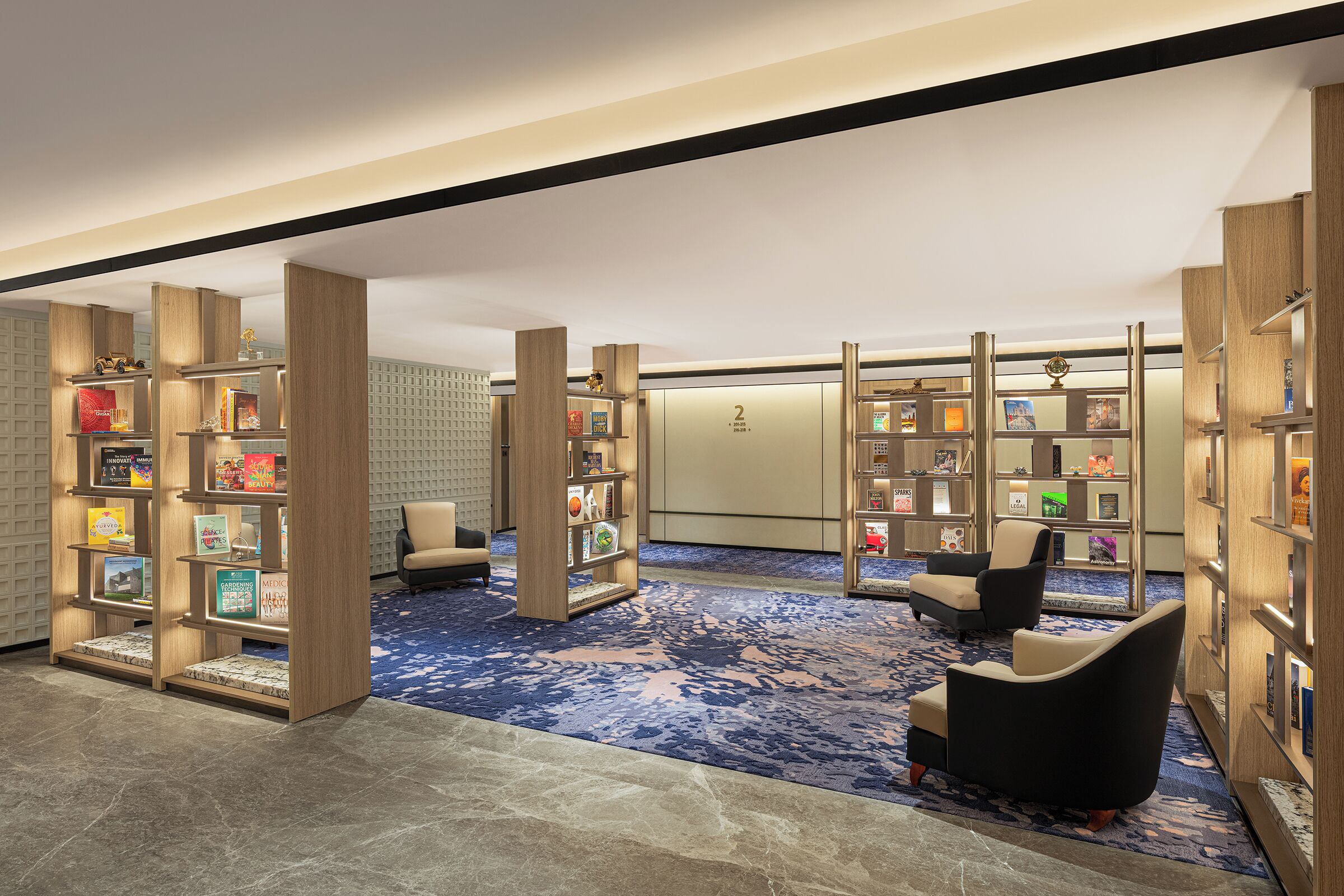 Eine moderne Bibliothek mit Bücherregalen, Teppichboden und einer Sitzgelegenheit.