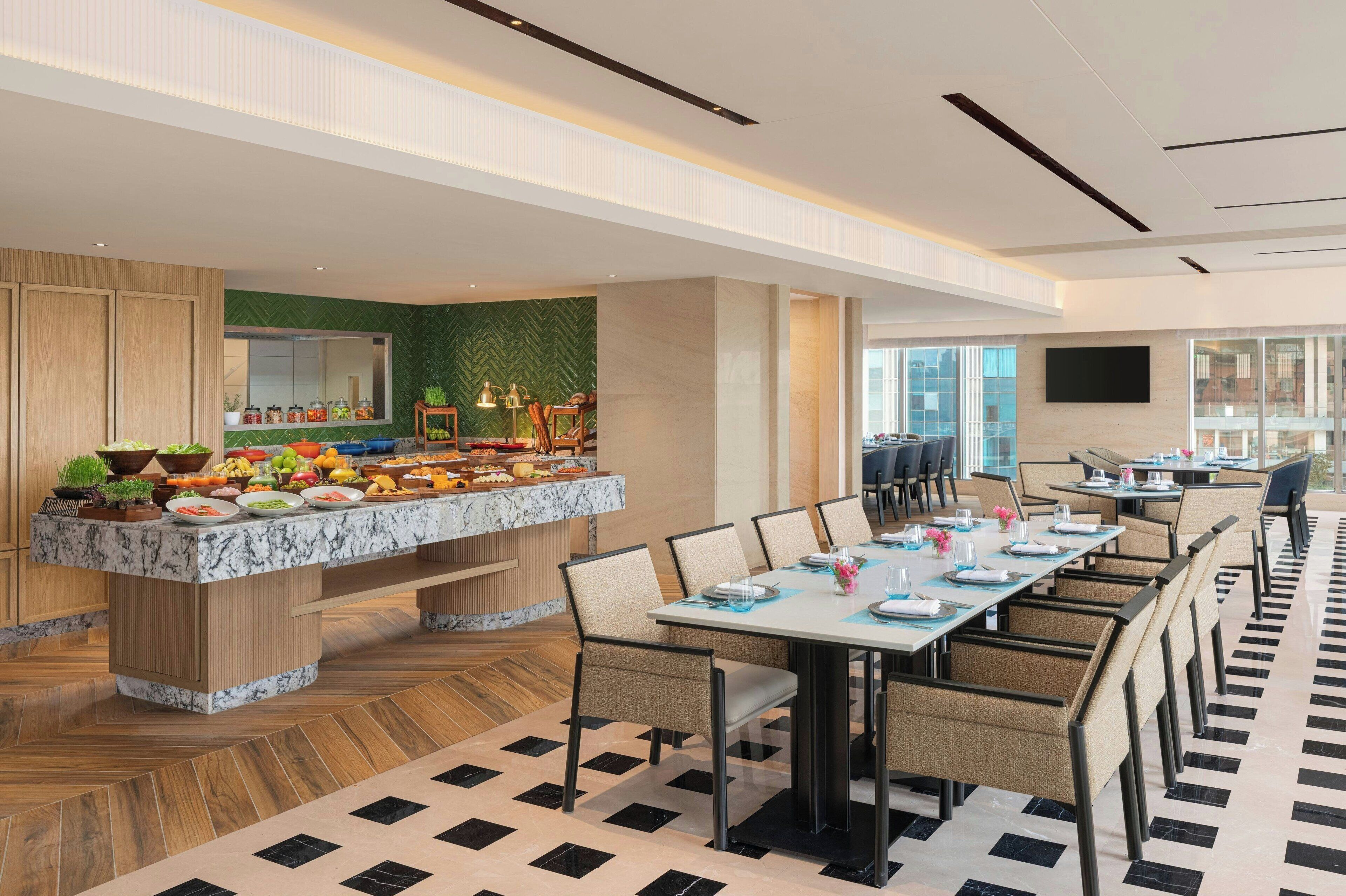 A modern dining area with a buffet, multiple tables, and chairs.