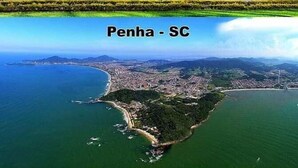 An aerial view of Penha Island with a coastal town, clear skies, and numerous boats in the water. - Pousada Morada Dos Anjos (Penha)