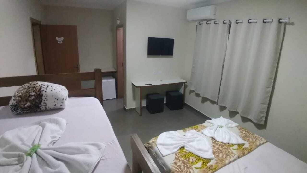 Una habitación de hotel con dos camas, un escritorio, un televisor y zona de ducha.