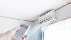 A hand holding a remote control near an air conditioning unit mounted on a wall. - Pousada Morada Dos Anjos (Penha)