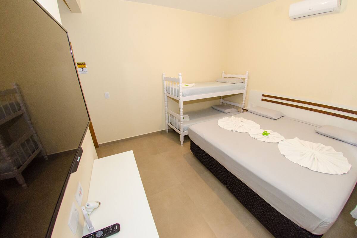 Hotellihuone, jossa on kerrossängyt, työpöytä tuolilla ja yöpöytä.