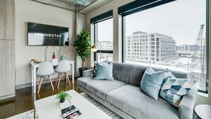 A modern living room with a grey sofa, a coffee table, and a TV displaying 'MINNESTAY'. - MINNeSTAY* Sable 401 - Studio | North Loop | Target Center (Minneapolis)