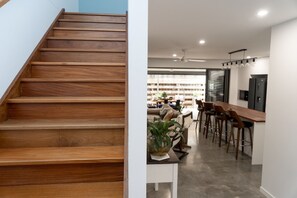 Eine Holztreppe führt zu einer modernen Küche mit Bar.