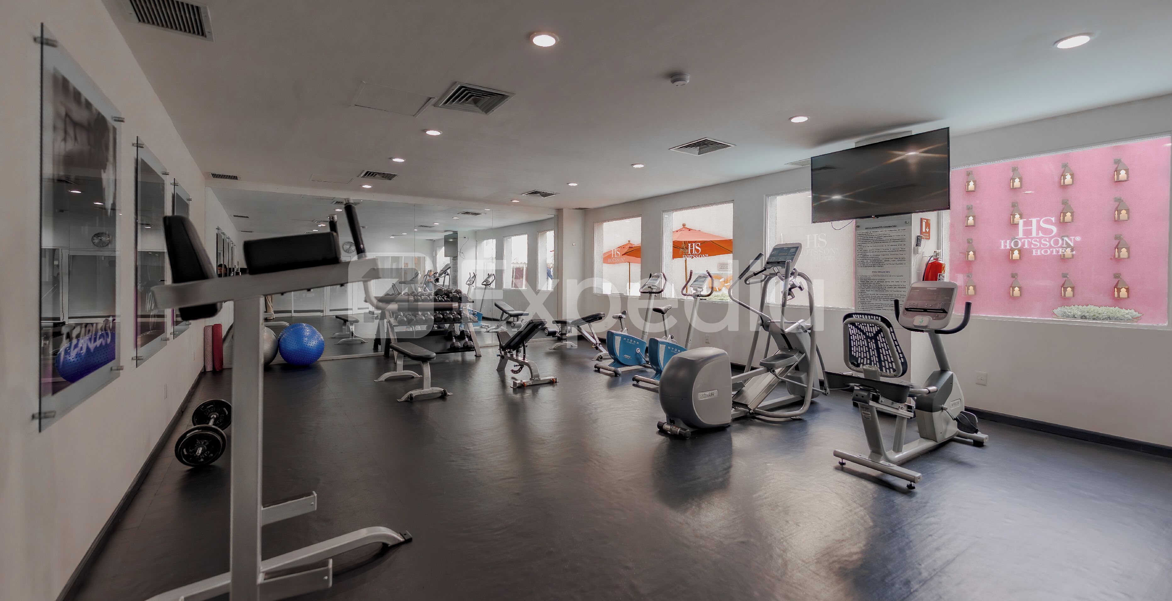 Un gimnasio con equipos de ejercicio variados, incluyendo cintas de correr y máquinas de pesas.