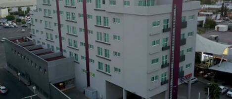 Un edificio de varios pisos con un llamativo letrero 'HS' en la fachada, probablemente indicando un hotel u otro establecimiento similar.