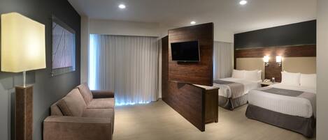 A modern hotel room with a sofa, two beds, a flat-screen TV, and a large window with curtains.