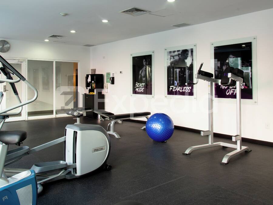 Un gimnasio con equipo de ejercicio, una pelota de ejercicio azul y carteles motivacionales en la pared.