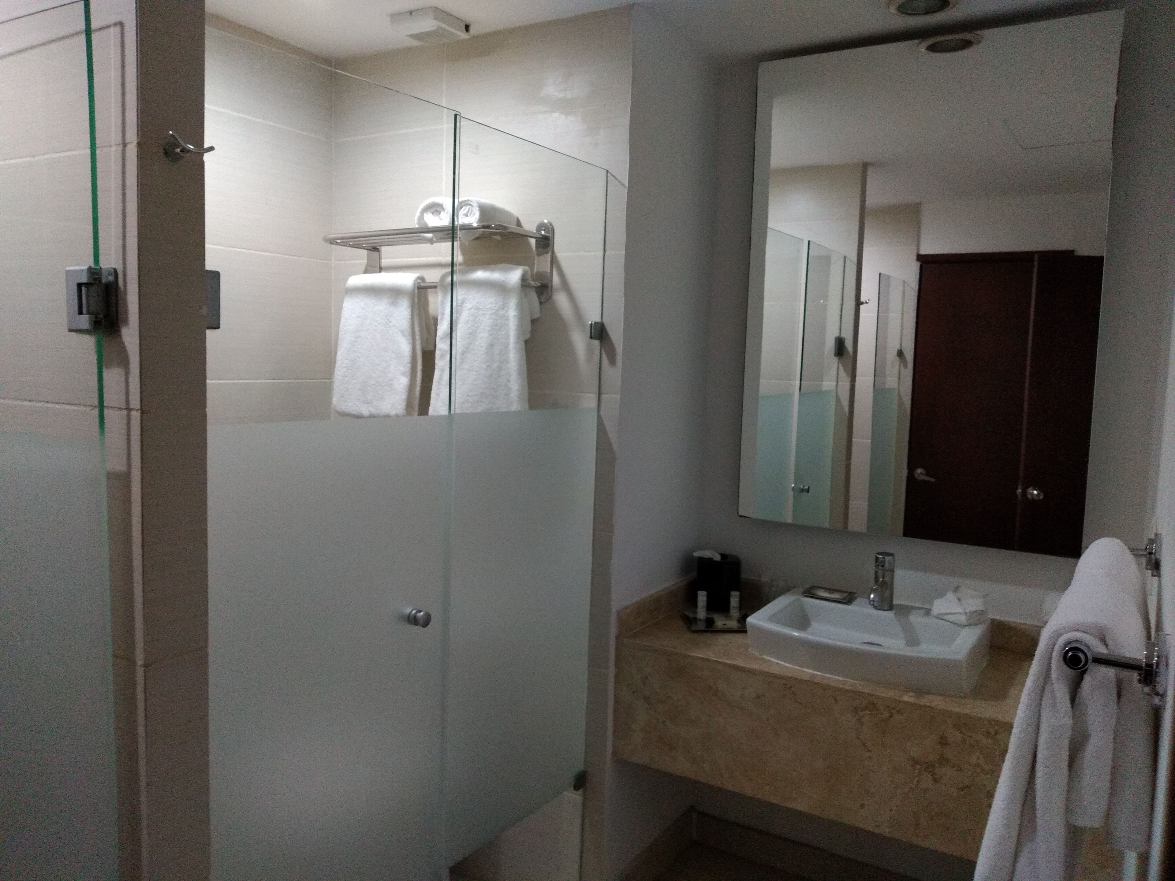 Un baño moderno con cabina de ducha de vidrio, un lavamanos con espejo y un perchero para toallas.